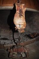 asado cucinando nel antico camino foto