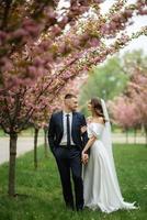 Novelli sposi camminare nel il parco tra ciliegia fiori foto