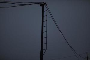 fili su polo. elettrico fili su sfondo di grigio cielo. deprimente Guarda. foto