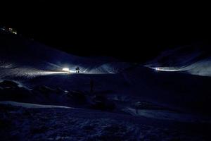 gatto delle nevi su sciare correre a notte foto