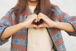 asiatico donna fabbricazione un' cuore con sua mani foto