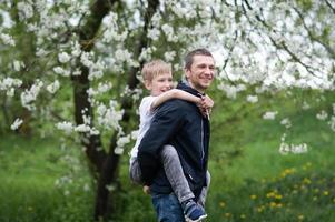 il ragazzo è seduta su di papà indietro e essi siamo ridendo foto