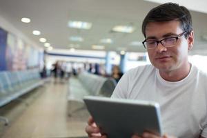 uomo che legge su un tablet durante l'attesa in aeroporto foto