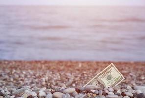 centinaio dollari metà coperto con il giro rocce menzogna su spiaggia foto