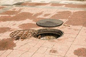 un Aperto tombino su il strada. pericoloso Aperto non garantito schiudere su il strada. incidente con fogna schiudere nel città. concetto di liquami, riparazione di metropolitana comunicazioni foto