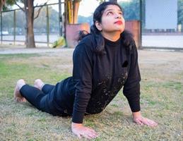 giovane indiano donna praticante yoga all'aperto nel un' parco. bellissimo ragazza pratica di base yoga posa. quiete e relax, femmina felicità. di base yoga pose all'aperto foto