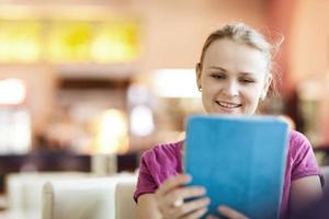 donna felice in un caffè utilizzando una tavoletta foto