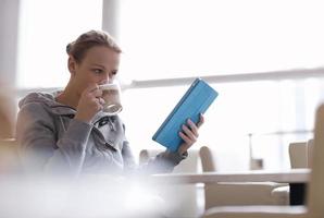 donna sorseggiando caffè e guardando un tablet foto