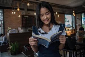 giovane donna che legge il libro seduto al chiuso in urban cafe foto