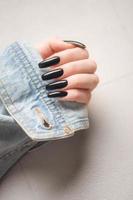 mano di un' giovane ragazza con nero manicure su Chiodi foto