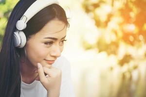 ritratto di una ragazza sorridente con le cuffie che ascolta la musica in natura foto