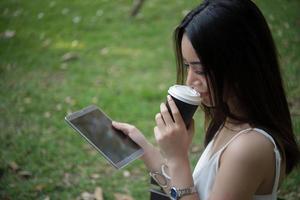 giovane bella donna che tiene tazza di caffè usa e getta e smartphone all'aperto