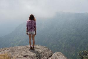 posteriore di un escursionista in piedi sulla cima di una montagna e godersi la vista della natura foto