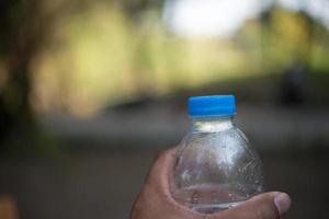 bottiglia d'acqua con sfondo natura sfocata e spazio di copia foto