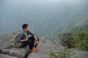 escursionista giovane hipster con zaino seduto sulla cima della montagna