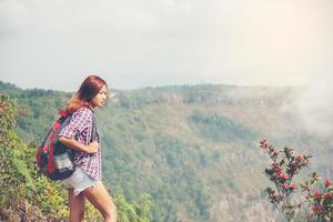 escursionista con zaino in piedi sulla cima di una montagna e godersi la vista della natura foto