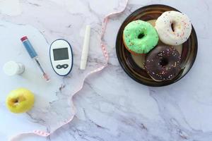 strumenti di misurazione del diabete, insulina e ciambelle su sfondo bianco foto