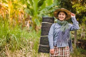 giovane bella contadino donna in piedi su terreni agricoli e ispezionando agricolo colture foto