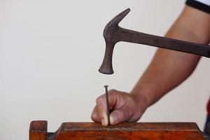 avvicinamento falegname mano usi martello per colpire chiodo. concetto, carpenteria e costruzione Strumenti. riparazione o fissaggio, Fai da te lavorazione del legno. foto