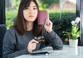 giovane donna seduta che mostra passaporto e carta di credito foto