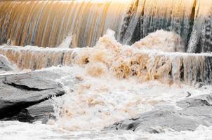 cascata cascata streaming giù nel il verde foresta, schiumante acqua In arrivo al di sopra di un' piccolo cascata a partire dal un' diga foto