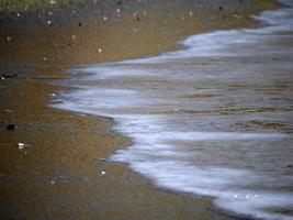 mare onda schiuma su il sabbia spiaggia riva foto