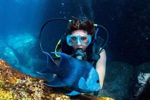 bellissimo latina tuffatore ragazza mentre toccante un' pesce foto