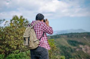 giovane zaino in spalla uomo uso telecamera per prendere immagini nel foresta. foto