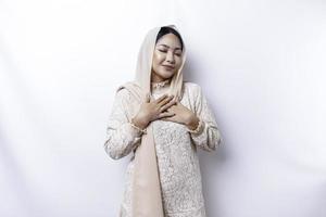 contento memore grato giovane asiatico musulmano donna con sua mano su sua il petto sorridente isolato su bianca sfondo foto