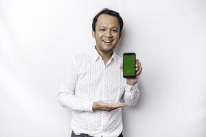un' ritratto di un' sorridente asiatico uomo indossare un' bianca camicia e mostrando verde schermo su sua Telefono, isolato di bianca sfondo foto
