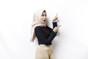 scioccato asiatico musulmano donna puntamento a il copia spazio su accanto suo, isolato di bianca sfondo foto