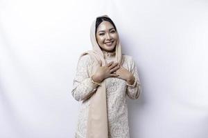 contento memore grato giovane asiatico musulmano donna con sua mano su sua il petto sorridente isolato su bianca sfondo foto