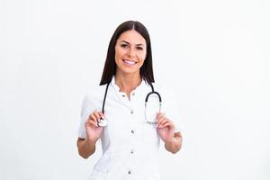 donna medico indossare bianca cappotto stetoscopio su le spalle guardare a telecamera. fiducioso femmina medico sorridente a telecamera, Salute cura e prevenzione concetto foto