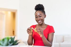 giovane africano americano donna è lettura un' Messaggio a partire dal fortuna biscotti, fa il carta dentro di il biscotti raccontare voi bene cose o foto