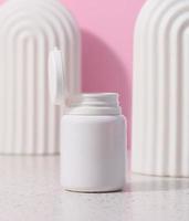 bianca plastica vaso con un Aperto coperchio per cosmetici e medico preparazioni su un' rosa sfondo foto