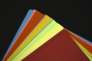 multicolore lenzuola di carta su un' nero sfondo. colorato ufficio carta. un' imballare di colorato carta. foto