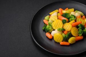 delizioso fresco verdure al vapore carote, broccoli, cavolfiore su un' nero piatto foto