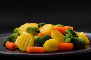 delizioso fresco verdure al vapore carote, broccoli, cavolfiore su un' nero piatto foto