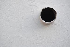 buco nero su un muro bianco foto