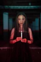 un' donna adorazione Satana Tenere un' candela nel sua mano quando un' rituale è andando per essere tenuto a un' cimitero foto