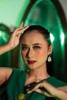il viso con bellissimo trucco e rosso labbra di un asiatico donna nel un' verde vestito e gioielleria foto