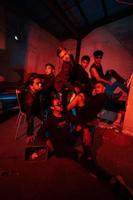un' gruppo di asiatico adolescenti nel nero Abiti in posa molto cattivo con loro amici nel un' magazzino con un' rosso leggero foto