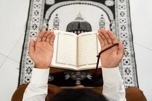 persona preghiere nel moschea con sfondo di Corano libro foto
