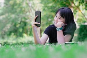 una ragazza seduta in giardino con il suo telefono foto
