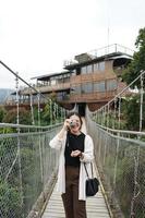 asiatico donna viaggiatore in piedi su un' sospeso ponte foto