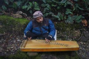 un' uomo giocando kecapi tradizionale sundanese musica nel il ciwidey, bandung, ovest Giava, Indonesia. foto