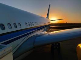 silhouette di un' passeggeri aereo atterraggio su il aeroporto grembiule contro il fondale di il pittoresco arancia tramonto cielo foto