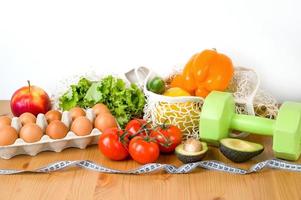 verdura, frutta e uova vicino manubri e misurazione nastro. sport e dieta concetto. salutare stile di vita foto