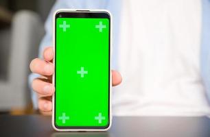 avvicinamento modello Immagine di un' uomo Tenere e mostrandosmartphone con verde croma schermo foto