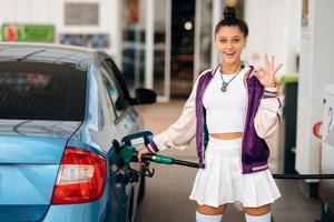 donna Riempimento sua auto con carburante a un' gas stazione foto